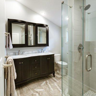 浴室配有玻璃淋浴，黑色梳妆台和镜面倾斜天花板   